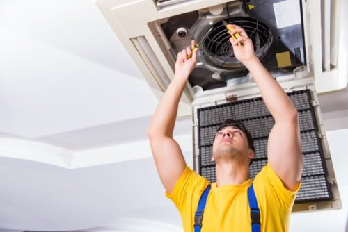 Repairman repairing ceiling air conditioning unit